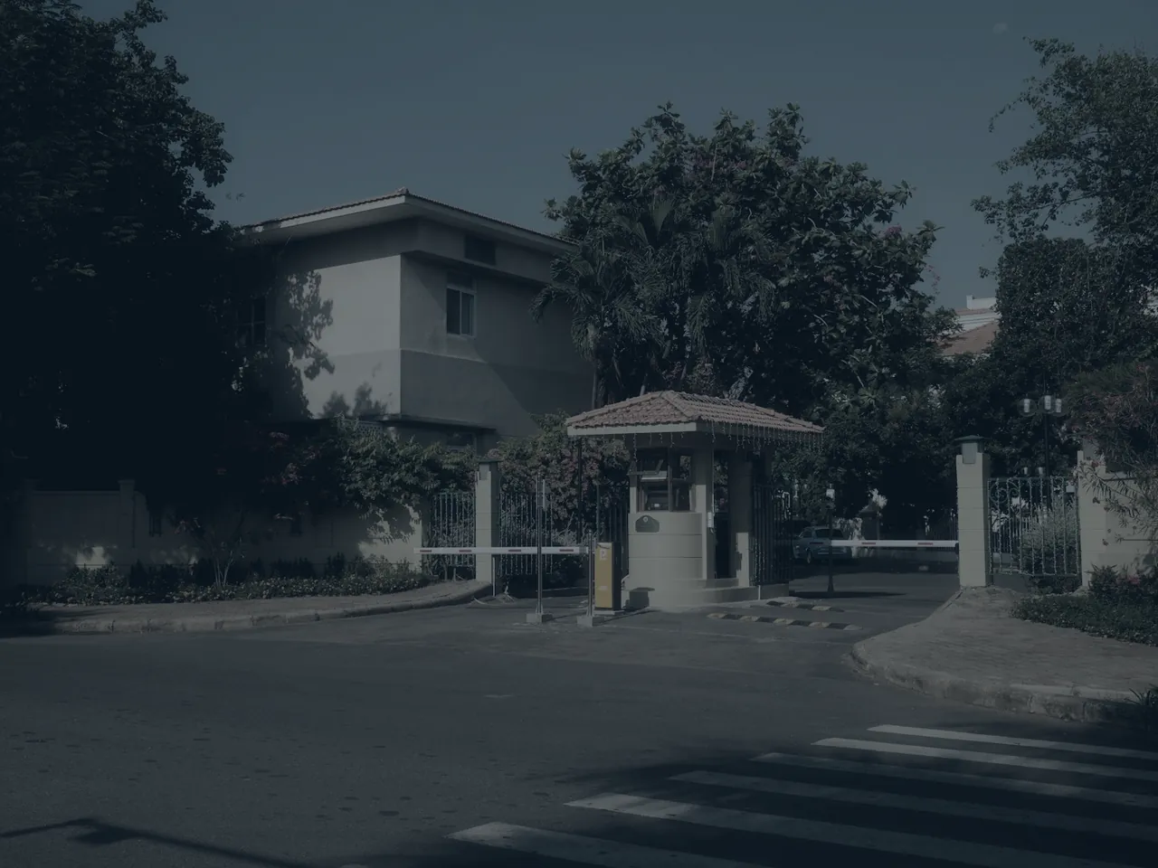 A gated residential estate entrance with a guard house and boom controlling vehicle access